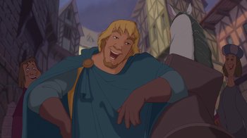 Movie still from “The Hunchback of Notre Dame” (1996), directed by Gary Trousdale – A man with a beard is smiling for the camera; Medium shot, Over the shoulder angle