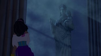 Movie still from “The Hunchback of Notre Dame” (1996), directed by Gary Trousdale – A statue of a woman holding a child in her arms in front of a building; Medium shot, Low angle