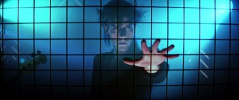 Movie still from “The Hunger” (1983), directed by Tony Scott – A woman in a black shirt is behind a glass wall; Medium shot, Low angle