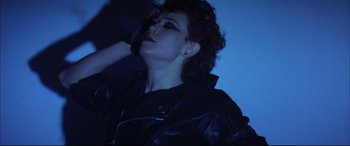 Movie still from “The Hunger” (1983), directed by Tony Scott – A woman in a leather jacket is looking up; Close Up shot, Low angle