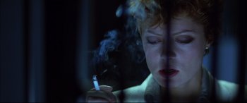 Movie still from “The Hunger” (1983), directed by Tony Scott – A woman is smoking a cigarette in a dark room; Close Up shot, Low angle