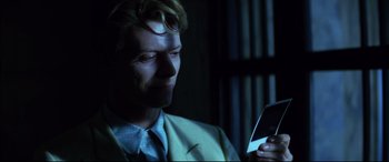 Movie still from “The Hunger” (1983), directed by Tony Scott – A man looking at his cell phone in the dark; Close Up shot, Over the shoulder angle