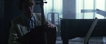Movie still from “The Hunger” (1983), directed by Tony Scott – A man holding a double bass in front of a grand piano; Medium shot, Over the shoulder angle