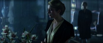 Movie still from “The Hunger” (1983), directed by Tony Scott – A beautiful woman holding a white flower in a room; Close Up shot, Over the shoulder angle