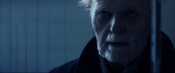 Movie still from “The Hunger” (1983), directed by Tony Scott – An old man with white hair and blue eyes stares at the camera; Close Up shot, Over the shoulder angle