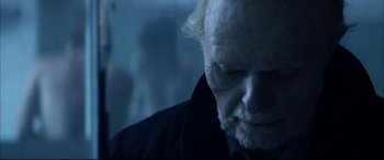 Movie still from “The Hunger” (1983), directed by Tony Scott – An old man with a beard is looking at the camera; Close Up shot, Over the shoulder angle