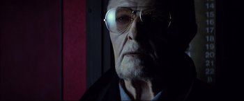 Movie still from “The Hunger” (1983), directed by Tony Scott – An old man wearing glasses looking at the camera; Close Up shot, Low angle