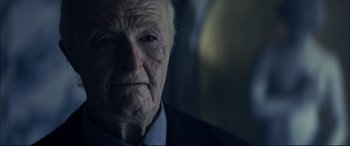 Movie still from “The Hunger” (1983), directed by Tony Scott – An old man with a wrinkled face looking at the camera; Close Up shot, Over the shoulder angle