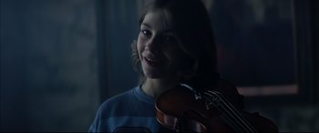 Movie still from “The Hunger” (1983), directed by Tony Scott – A young girl holding a violin in a dark room; Close Up shot, Over the shoulder angle