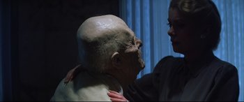 Movie still from “The Hunger” (1983), directed by Tony Scott – A woman is touching the face of a fake head; Close Up shot, Over the shoulder angle