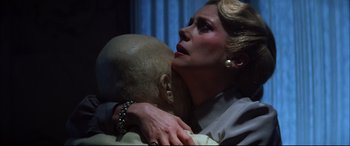 Movie still from “The Hunger” (1983), directed by Tony Scott – A woman holding a man's head in a room; Close Up shot, Low angle