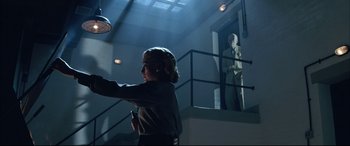 Movie still from “The Hunger” (1983), directed by Tony Scott – A woman holding a cell phone while standing in a room; Wide shot, Low angle