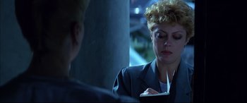 Movie still from “The Hunger” (1983), directed by Tony Scott – A woman is writing on a piece of paper in front of another woman; Close Up shot, Over the shoulder angle