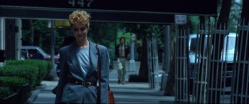 Movie still from “The Hunger” (1983), directed by Tony Scott – A woman walking down the street in a suit; Medium shot, Low angle
