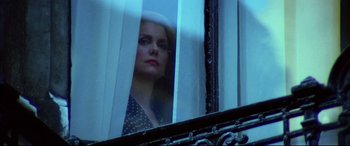 Movie still from “The Hunger” (1983), directed by Tony Scott – A woman looking out of a window at night; Close Up shot, Low angle