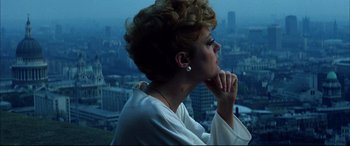 Movie still from “The Hunger” (1983), directed by Tony Scott – A woman in a white shirt looking out over a city; Close Up shot, Low angle