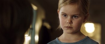 Movie still from “The Hunt” (2012), directed by Thomas Vinterberg – A little girl is looking into the camera; Close Up shot, Over the shoulder angle
