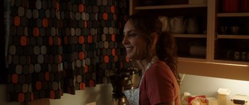 Movie still from “The Hunt” (2012), directed by Thomas Vinterberg – A woman smiles while standing in front of a coffee maker; Medium shot, Over the shoulder angle