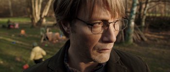Movie still from “The Hunt” (2012), directed by Thomas Vinterberg – A person wearing glasses and a jacket; Close Up shot, Over the shoulder angle