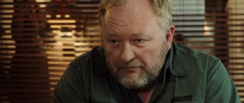 Movie still from “The Hunt” (2012), directed by Thomas Vinterberg – A person wearing a green shirt; Close Up shot, Over the shoulder angle