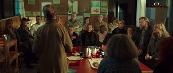Movie still from “The Hunt” (2012), directed by Thomas Vinterberg – A group of people sitting at a table with food; Wide shot, Over the shoulder angle