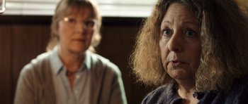 Movie still from “The Hunt” (2012), directed by Thomas Vinterberg – Two women standing next to each other in front of a window; Close Up shot, Over the shoulder angle