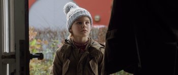 Movie still from “The Hunt” (2012), directed by Thomas Vinterberg – A little girl wearing a winter hat looking at a person; Close Up shot, Over the shoulder angle