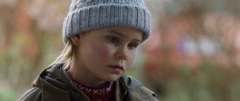 Movie still from “The Hunt” (2012), directed by Thomas Vinterberg – A little girl wearing a hat and a jacket; Close Up shot, Over the shoulder angle