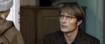 Movie still from “The Hunt” (2012), directed by Thomas Vinterberg – A person wearing glasses and a jacket; Close Up shot, Over the shoulder angle