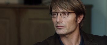 Movie still from “The Hunt” (2012), directed by Thomas Vinterberg – A person wearing glasses and a jacket; Close Up shot, Over the shoulder angle