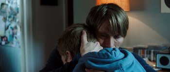 Movie still from “The Hunt” (2012), directed by Thomas Vinterberg – A man and a boy are hugging in a room; Close Up shot, Overhead angle