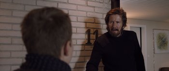 Movie still from “The Hunt” (2012), directed by Thomas Vinterberg – A man with a beard and a mustache is talking to another man; Medium shot, Over the shoulder angle
