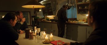 Movie still from “The Hunt” (2012), directed by Thomas Vinterberg – A man standing at a kitchen counter preparing food; Wide shot, Over the shoulder angle