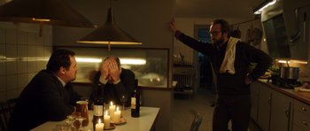 Movie still from “The Hunt” (2012), directed by Thomas Vinterberg – A man standing in front of a table with candles; Medium shot, High angle