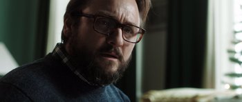 Movie still from “The Hunt” (2012), directed by Thomas Vinterberg – A person with a beard wearing glasses; Close Up shot, Over the shoulder angle