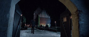 Movie still from “The Hunt” (2012), directed by Thomas Vinterberg – Two people are standing in the snow near a building at night; Extreme Wide shot, Low angle