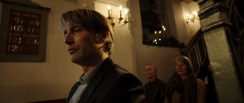 Movie still from “The Hunt” (2012), directed by Thomas Vinterberg – A man and a woman standing next to each other in a room; Close Up shot, Low angle