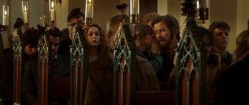 Movie still from “The Hunt” (2012), directed by Thomas Vinterberg – A group of people standing in front of candles; Close Up shot, Over the shoulder angle