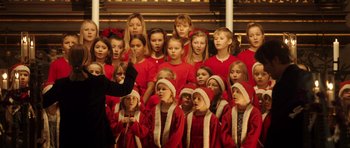 Movie still from “The Hunt” (2012), directed by Thomas Vinterberg – A group of young girls in red shirts and white hats singing together; Medium shot, High angle