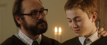 Movie still from “The Hunt” (2012), directed by Thomas Vinterberg – A man and a young boy standing next to each other in front of candles; Close Up shot, Over the shoulder angle
