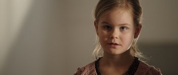 Movie still from “The Hunt” (2012), directed by Thomas Vinterberg – A little girl is looking into the camera; Close Up shot, Over the shoulder angle