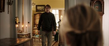 Movie still from “The Hunt” (2012), directed by Thomas Vinterberg – A man is walking through a room with a suitcase; Medium shot, Over the shoulder angle