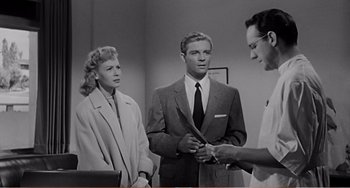 Movie still from “The Incredible Shrinking Man” (1957), directed by Jack Arnold – Two men and a woman in a room; Medium shot, Over the shoulder angle