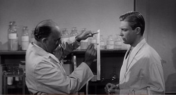 Movie still from “The Incredible Shrinking Man” (1957), directed by Jack Arnold – Two men in white lab coats in front of jars; Medium shot, Low angle