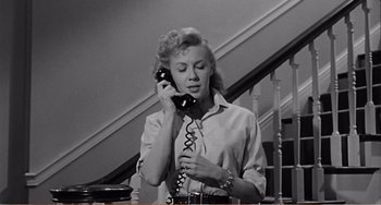 Movie still from “The Incredible Shrinking Man” (1957), directed by Jack Arnold – An old photo of a woman holding a phone to her ear; Medium shot, Low angle