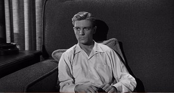 Movie still from “The Incredible Shrinking Man” (1957), directed by Jack Arnold – A black and white photo of a man sitting in a chair; Medium shot, Low angle