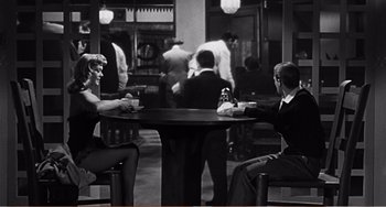 Movie still from “The Incredible Shrinking Man” (1957), directed by Jack Arnold – Two men sitting at a table in a restaurant; Wide shot, High angle