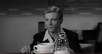 Movie still from “The Incredible Shrinking Man” (1957), directed by Jack Arnold – A man sitting at a table with a cup of coffee; Close Up shot, Over the shoulder angle