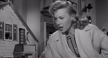 Movie still from “The Incredible Shrinking Man” (1957), directed by Jack Arnold – A black - and - white photo of a woman in a coat; Medium shot, Low angle