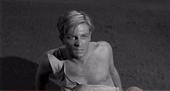 Movie still from “The Incredible Shrinking Man” (1957), directed by Jack Arnold – Black and white photograph of a shirtless man in the sand; Close Up shot, High angle